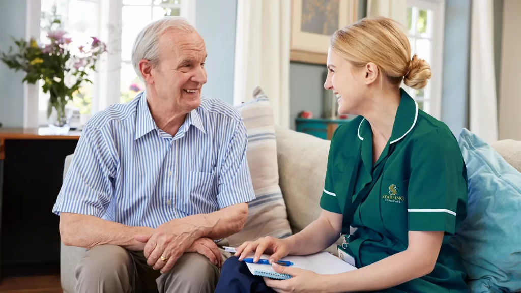 Smiling Starling Homecare carer supporting elderly man at home Smiling Starling Homecare carer talking with an elderly man, showing compassionate home care for older adults.