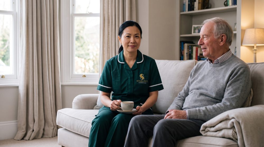 cancer-support-hertfordshire-carer-sitting-room A Starling Homecare carer with a cup of tea beside an older gentleman on his sofa, cancer support in Hertfordshire at home