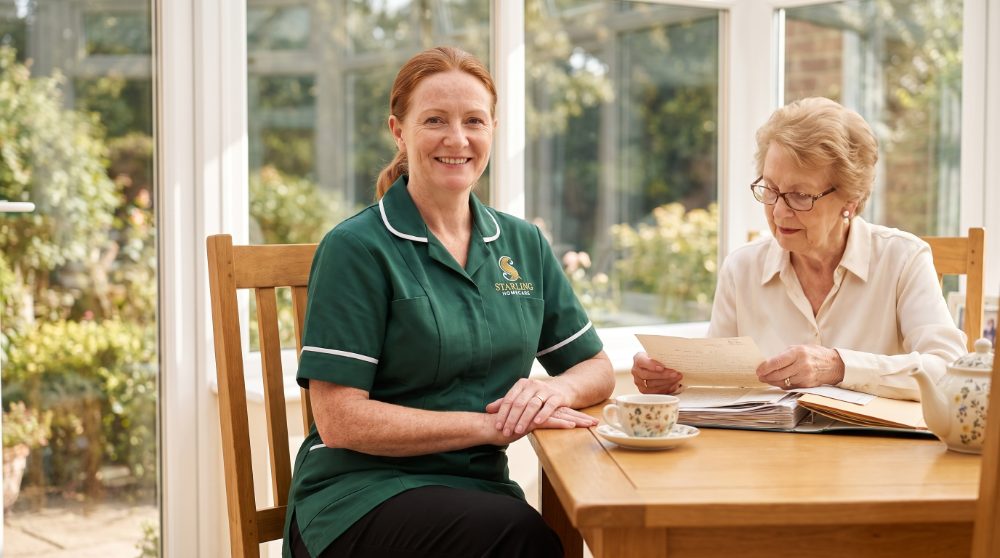 A Starling Homecare carer at a conservatory table with an older woman in Harpenden as she looks through the family papers that hold her enduring power of attorney in Harpenden