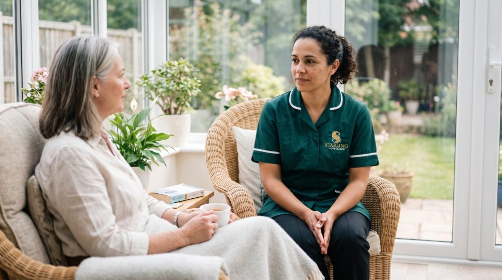 A Starling Homecare carer talking with a woman in her sixties in a conservatory during an MS respite care visit in Hertfordshire