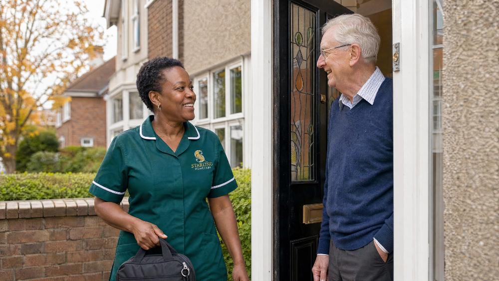 How often should carers visit an older parent? Carer and older man looking at a weekly planner of home care visit times at his kitchen table in Welwyn Garden City